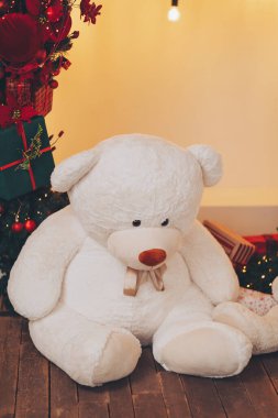 Noel ağacının yanında peluş bir oyuncak ayı olan rahat bir tatil sahnesi. Oyuncak ayı Noel ağacının arka planında