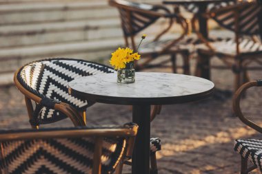Çiçekli kafe masası. Gündüz vakti bir Fransız restoranında bir masaya yakın çekim yapmak. Avrupa 'da masa ve sandalyeli bir kahve terası manzarası