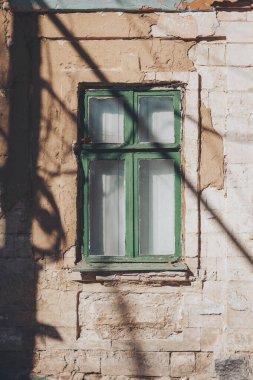 Gölgeli eski bir evin eski, eski, ahşap penceresi. Yıpranmış odundan yapılmış terk edilmiş ev yapımı. 