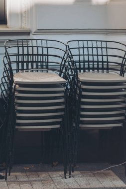 Kafe terasının yanında bir yığın karanlık sandalye var. Sezon sonu. Kış tatilinde sandalyeler. 