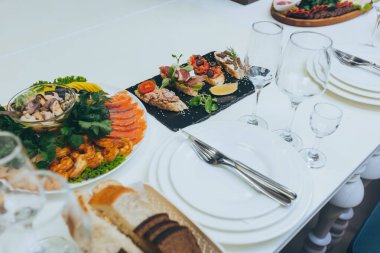 Tatil yemeği masası. Tabaklara yerleştirilmiş gurme yemekleri, restoran masası. Lüks, modern restarAunt 'da akşam ziyafeti veriyordu. Şarap kadehleri ve abur cuburlarla dolu restoran masası..