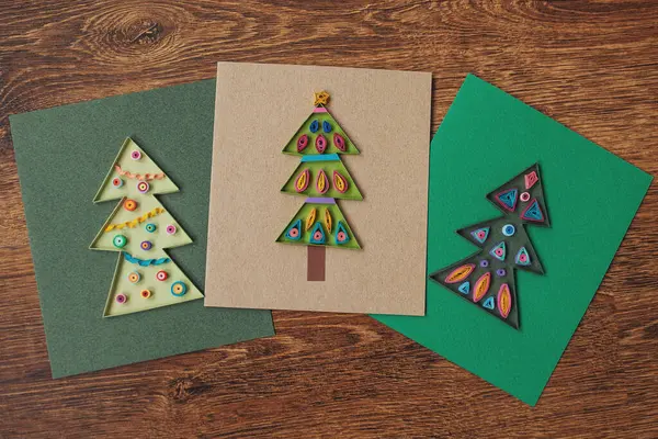 Kağıttan yapılmış Noel ağacı olan üç tane quilling kartı. Tebrik kartları hazırlıyorum. El yapımı kağıt tüy dökme tekniği. Evde el işi. Hobi, ev ofisi..