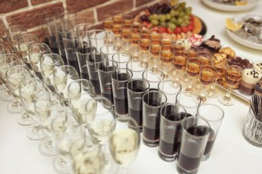 Açık büfe masasında bir sürü alkol içeceği, yemek servisi. Restoranda ya da barda bardakta farklı alkollü içecekler..