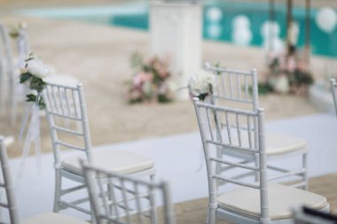 Doğanın bağrında bir tören. Çimlere çiçek konmuş beyaz sandalyeler. Beyaz sandalyeler, bir buket beyaz çiçekle birlikte bir etkinlik için dizildiler..