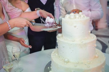 Düğün pastasını kesen gelin ve damat. Düğün ziyafetinde düğün pastası. Eller pastayı kessin.