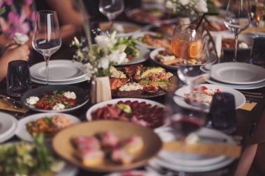 Arkadaşların ev partisi için farklı lezzetli yiyecek ve içeceklerle kahvaltı masası hazırlamak. Masada çeşitli yiyecekler, balık, zeytin, ekmek, ahududu, et.