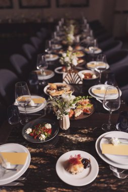 Restoran salonundaki parlak ve şenlikli masa. Lokantada masa ayarlandı. Arkadaşların ev partisi için farklı lezzetli yemeklerle kahvaltı masası hazırlamak. Masada çeşitli yiyecekler var.