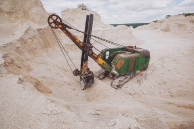 old excavator stands on the territory of a chalk quarry. A quarry excavator loader on a construction site during the extraction of crushed stone or limestone.  clipart