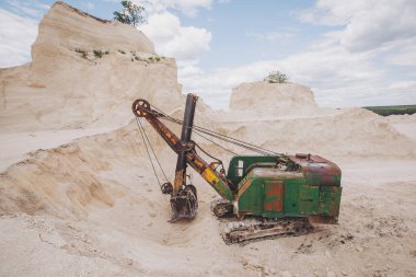 old excavator stands on the territory of a chalk quarry. A quarry excavator loader on a construction site during the extraction of crushed stone or limestone.  clipart