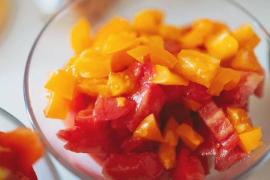 Pişirilmeye ya da kızartılmaya hazır sebzeleri kes. Kesme tahtasında kesilmiş sebzeler. Doğranmış dolmalık biber, domates ve soğan. Üst görünüm.