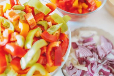 Pişirilmeye ya da kızartılmaya hazır sebzeleri kes. Kesme tahtasında kesilmiş sebzeler. Doğranmış dolmalık biber, domates ve soğan. Üst görünüm.