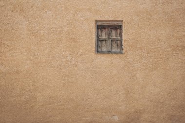 Soluk sarı duvardaki eski pencere. Geleneksel eski ev duvarı ve ahşap pencere.