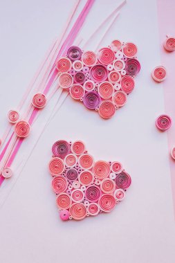 Kalem kağıdı ve pembe kağıt kalp. Sevgililer günün kutlu olsun. El yapımı kağıt tüy dökme tekniği. Evde el işi. Hobi, ev ofisi. Renkli kağıt kurdelelerden kalp. 