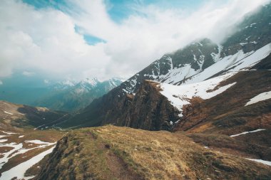 Güneşli ve bulutlu bir günde kısmen karla kaplı güzel bir kaya manzarası.. 