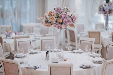 Güzel çiçek ve düğün masalarının mum süslemesi. Ziyafet masası ve dekorasyon. Masada çatal bıçak takımı var. Etkinlik partisi için masalar hazır. Lüks, zarif bir masa, bir restoranda yemek hazırlıyor.