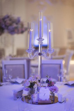 Güzel çiçek ve düğün masalarının mum süslemesi. Ziyafet masası ve dekorasyon. Masada çatal bıçak takımı var. Etkinlik partisi için masalar hazır. Lüks, zarif bir masa, bir restoranda yemek hazırlıyor.