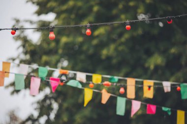 Parlak renklerde canlı bayraklar ve ağaçlar arasında şakacı fenerler asılıdır. Bu da öğleden sonra bir açık hava olayı için şenlikli bir atmosfer yaratır.
