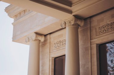 Mimari tasarım, ayrıntılı parşömen yazıları ve tabanları içeren zarif Korint sütunlarını sergiliyor. Güneş ışığı bir binanın işçiliğini ön plana çıkarıyor. 