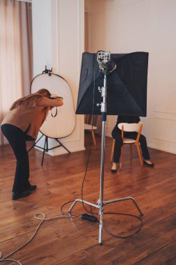 Yaratıcı stüdyo ayarı bir fotoğrafçının iyi ışıklandırılmış bir iç mekanda bir modelle benzersiz bir anı çekmesini gösteriyor.