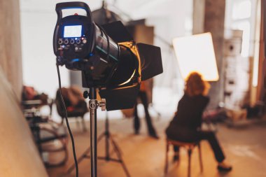 Bir seans sırasında sıcak ışık ve yaratıcı enerjiyle dolu bir fotoğraf stüdyosunda stüdyo flaşı üzerine odaklanmış büyüleyici sanatçılık gözler önüne seriliyor..