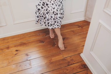 Sakin bir öğleden sonra güneşli bir odada, parlak ahşap zeminde sıcak ve zarif adımlar.