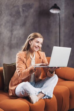 Serbest Çalışan, modern bir ev ortamında rahat bir kanepede çalışırken çevrimiçi olarak üretken anların tadını çıkarıyor