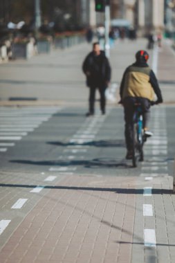 Şehrin göbeğinde güneşli bir öğleden sonra, hareketli bir şehir yolunda yol alan bisikletçi.