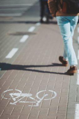 Yoğun bir şehir caddesinde yürürken, yayalar bir bisiklet şeridiyle aynı yolu paylaşıyor, hareketli bir şehir atmosferinde günlük yaşamı yakalıyorlar.