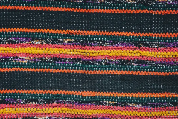 Canlı dokuma dokuması, hareketli bir zanaatkar pazarında geleneksel zanaatkarlık sergileyen sarı, beyaz ve siyah çizgilerin karmaşık bir desenini ortaya koyuyor.