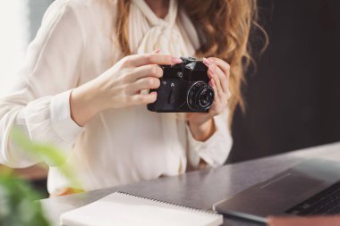 Evde kamerayla çalışan Freelancer rahat bir ofiste fotoğraf çekimine hazırlanıyor. Rahat bir ev ofisinde, bir serbest çalışan masa başında otururken kamerasını ayarlar..