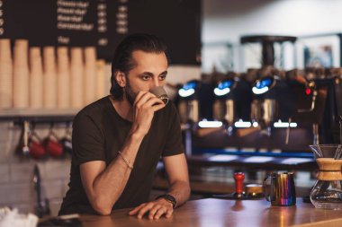 Barista, hareketli bir şehirde sıcak bir kafede kahve hazırlarken bir anlık düşüncelere dalmaktan zevk alır.