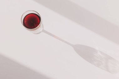 Güneş ışığında kırmızı şarap parıldıyor. Beyaz bir yüzeyde zarif gölgeler bırakıyor. Huzurlu bir ortamda zarif ayrıntıları ortaya çıkarıyor.