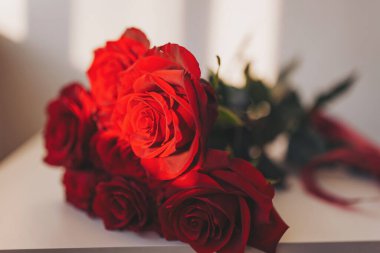 Güzel bir buket kırmızı gül, altın saat boyunca sıcacık bir ortamda aşkın sıcaklığını ve zarafetini yakalıyor.