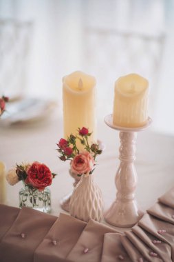Yumuşak pastel çiçek aranjmanları yumuşak ışık altında romantik bir kutlama için güzel bir masa hazırlar.