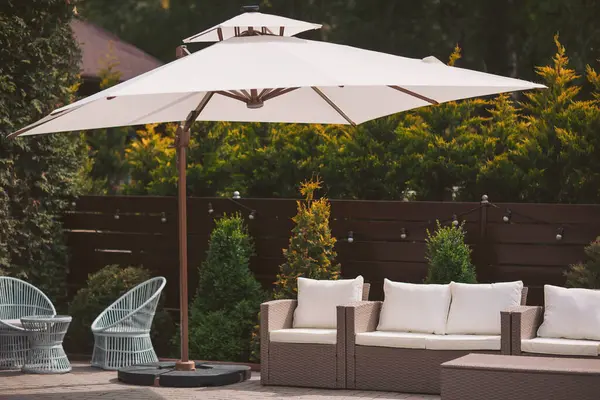 Güneşli bir öğleden sonra, yemyeşil bir bahçede, büyük beyaz bir şemsiyenin altında rahatlamak.. 