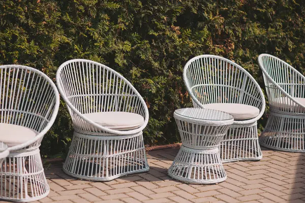 Güzel bir açık hava oturma düzeniyle yemyeşil bir arka plan güneşli bir öğleden sonra sıcacık bir bahçede rahatlamaya davetiye çıkarıyor.