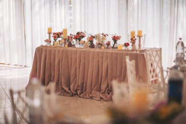 Parlak bir etkinlik alanında çiçekler ve mumlarla süslenmiş şık masa düzenlemesi güneşli bir öğleden sonra toplantısında