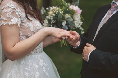 Şehvetli bir düğün çifti. Yeni evlilerin romantik anları. Düğün fotoğrafı. Gelinin özel gününde tuttuğu düğün çiçekleri buketi. Yüzükler yeni evlilerin ellerinde.