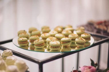 Gösterişli bir kutlama sırasında zarif bir yemek ortamında renkli tatlılar ve taze meyveler içeren enfes bir tatlı tabağı.