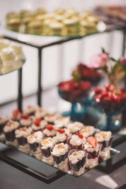 Gösterişli bir kutlama sırasında zarif bir yemek ortamında renkli tatlılar ve taze meyveler içeren enfes bir tatlı tabağı.