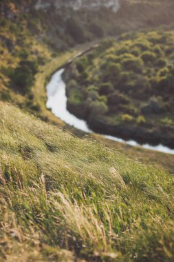 Sarmal nehir, gün batımında yemyeşil tepelerin arasından akar. Huzurlu bir manzaranın altın saatinde doğanın barışçıl güzelliğini yakalar.