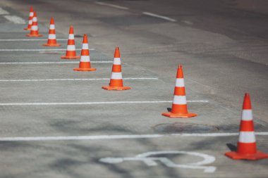 Turuncu nöbetçiler boş park alanlarının başında nöbet tutarlar. Varlıkları, kuralların, sınırların ve asfalt üzerinde otomobillerin dikkatli dansının sessiz bir hatırlatıcısıdır.