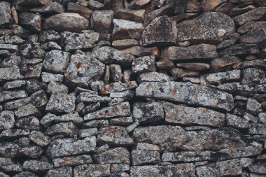 Günbatımının altın saatinde sakin bir kırsal alanda geleneksel duvar işçiliğini gösteren karmaşık taş duvar.