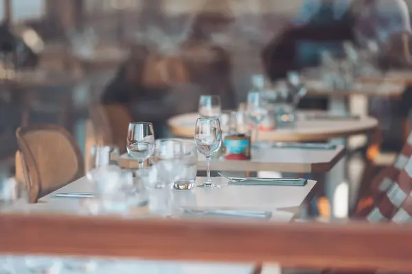 Restoranlar, zarif masaları ve sakin bir atmosferi olan modern bir restoranda akşam yemeği için hazırlanıyorlar.