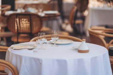 Sıcak bir günde deniz kenarındaki bir restoranda çatal bıçakla dışarıda yemek için masa hazır.