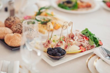 Parlak bir ortamda çeşitli lezzetler ve taze sebzeler sunan yemek dağıtımı. Bir ziyafet masasında çeşitli et, taze meyve ve zarif bir sunum sunan gurme tabağı