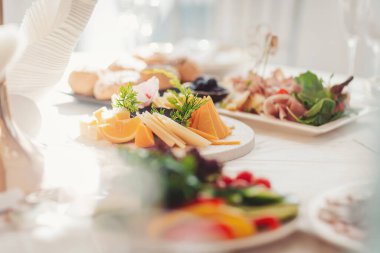 Parlak bir ortamda çeşitli lezzetler ve taze sebzeler sunan yemek dağıtımı. Bir ziyafet masasında çeşitli et, taze meyve ve zarif bir sunum sunan gurme tabağı