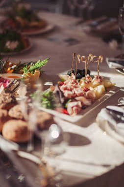 Parlak bir ortamda çeşitli lezzetler ve taze sebzeler sunan yemek dağıtımı. Bir ziyafet masasında çeşitli et, taze meyve ve zarif bir sunum sunan gurme tabağı