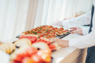 Zarif aperatiflerin yer aldığı enfes bir mutfak gösterisi bir şenlik toplantısında zarif bir açık büfe masasında düzenlendi. Yemek şirketi servis masasında bir dizi aperatif hazırlar.. 