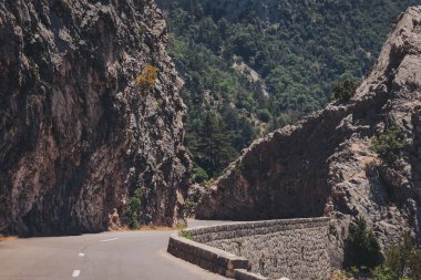 Sarmal yol, parlak güneş ışığı altında sakin bir kaçışta kayalık dağ manzarasını kucaklıyor.